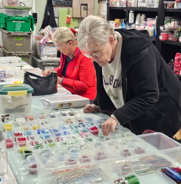 Workshop participants select colorful glass pieces from organized trays during a Glass Quiltopia fused glass class.