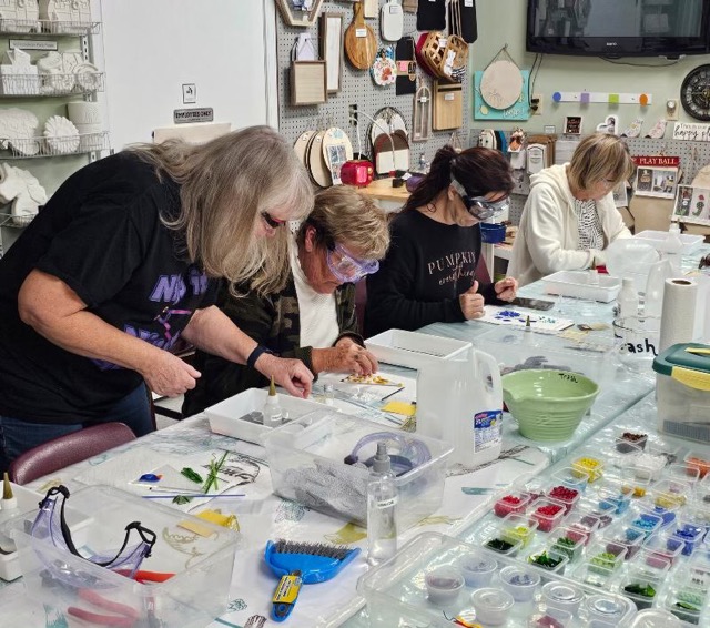Joanne Fransen-Gilliam assists participants as they work on fused glass projects at a Glass Quiltopia workshop table.